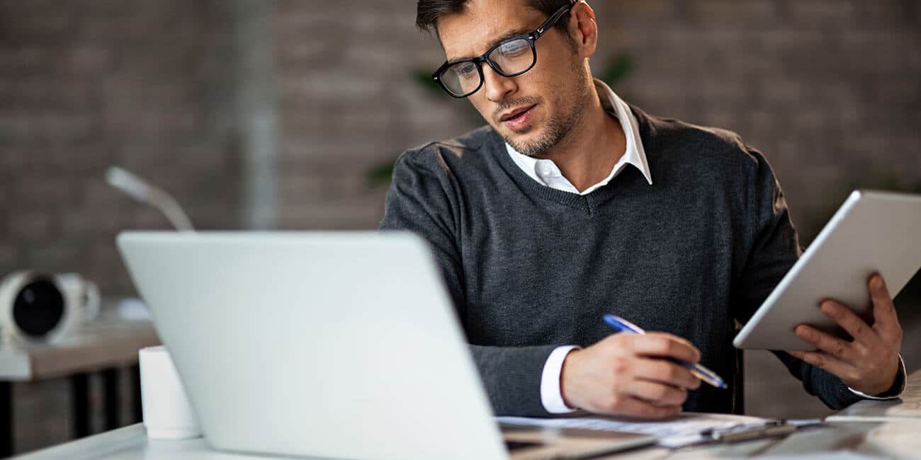 A manager reviewing analysis on his iPad and computer, examining the latest company findings.